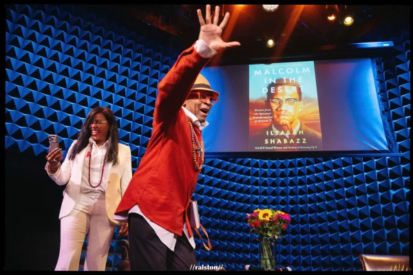 Spike Lee waves to audience on stage with Ilyasah Shabazz.

Photo Credit: @ralstonrsmith